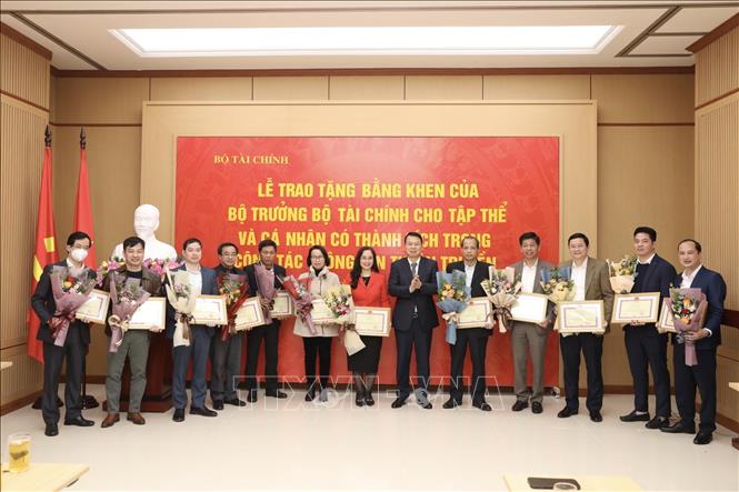Thứ trưởng Bộ Tài chính Nguyễn Đức Chi trao tặng Bằng khen của Bộ trưởng cho 12 tập thể có thành tích xuất sắc trong công tác thông tin, tuyên truyền. Ảnh: Minh Quyết - TTXVN