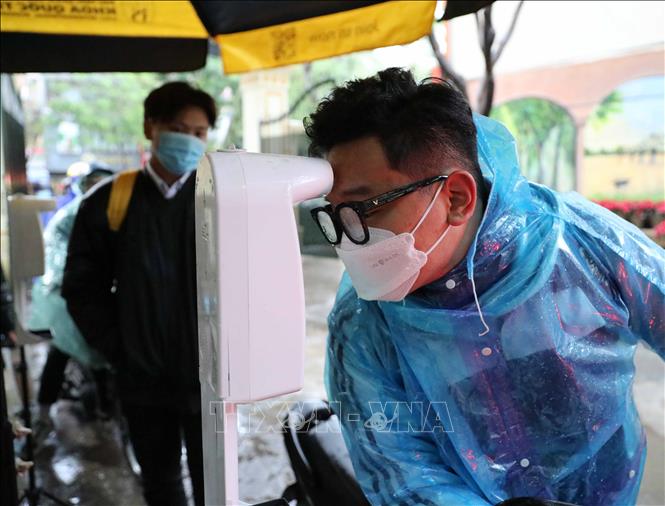 Trong ảnh: Học sinh lớp 12 trường THPT Việt Đức (quận Hoàn Kiếm) thực hiện đo thân nhiệt khi tới trường học trực tiếp từ sáng 17/1/2022. Ảnh: Thanh Tùng - TTXVN