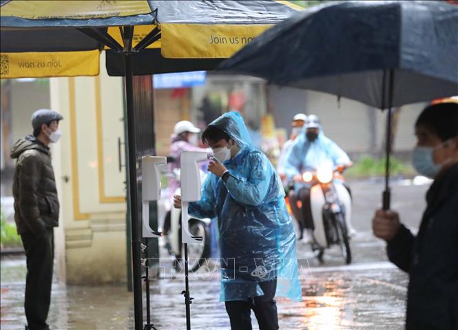 Trong ảnh: Học sinh lớp 12 trường THPT Việt Đức (quận Hoàn Kiếm) thực hiện đo thân nhiệt và sát khuẩn tay khi tới trường học trực tiếp từ sáng 17/1/2022. Ảnh: Thanh Tùng - TTXVN