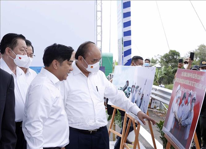 Chủ tịch nước Nguyễn Xuân Phúc xem trưng bày ảnh quá trình thi công Dự án tuyến đường cao tốc Trung Lương-Mỹ Thuận. Ảnh: Thống Nhất - TTXVN