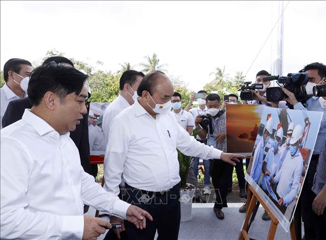 Chủ tịch nước Nguyễn Xuân Phúc xem trưng bày ảnh quá trình thi công Dự án tuyến đường cao tốc Trung Lương-Mỹ Thuận. Ảnh: Thống Nhất - TTXVN