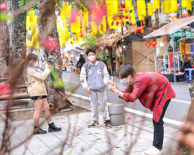 Các bạn trẻ chụp ảnh lưu niệm trên không gian bích hoạ phố Phùng Hưng. Ảnh: Tuấn Đức - TTXVN