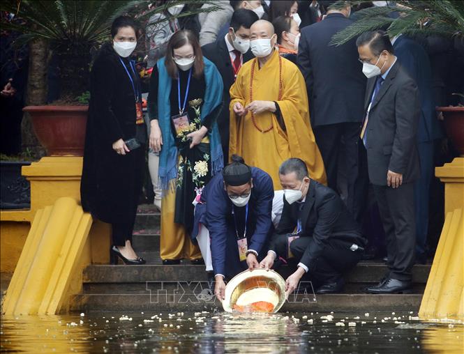 Các đại biểu và kiều bào thả cá tại Ao cá Bác Hồ trong Khu di tích Chủ tịch Hồ Chí Minh tại Phủ Chủ tịch. Ảnh: TTXVN
