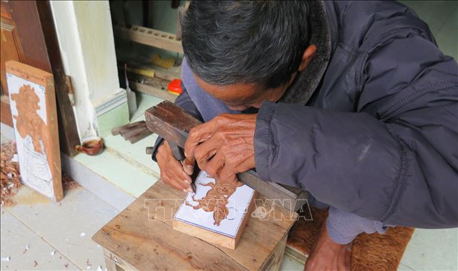 Trong ảnh: Nghệ nhân Kỳ Hữu Phước khắc mộc bản để in tranh. Ảnh: Tường Vi - TTXVN