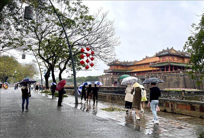 Du khách “đội mưa” đến tham quan Đại Nội Huế. Ảnh: Mai Trang/TTXVN