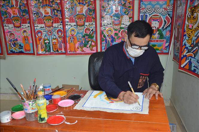 Trong ảnh: Ông Triệu Hùng Cường đang miệt mài vẽ những bộ tranh thờ với sự cẩn trọng, tỷ mỷ, và sự thấu hiểu về giá trị văn hóa của dân tộc mình qua mỗi bộ tranh. Ảnh: Hoa Mai - TTXVN
