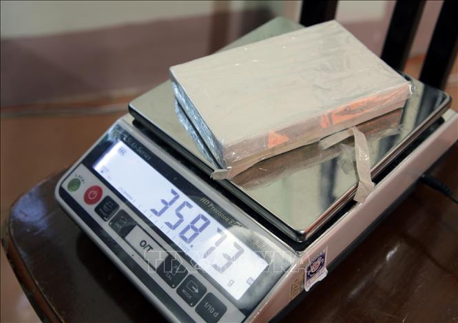 Các lực lượng chức năng thực hiện cân số heroin tang vật của vụ án. Ảnh: Quý Trung – TTXVN