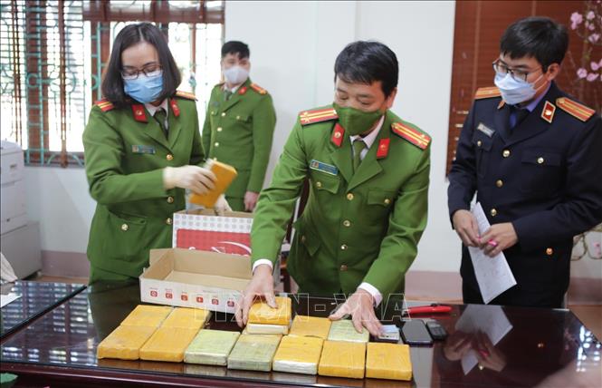 Các lực lượng chức năng kiểm tra cân số heroin tang vật của vụ án. Ảnh: Quý Trung – TTXVN