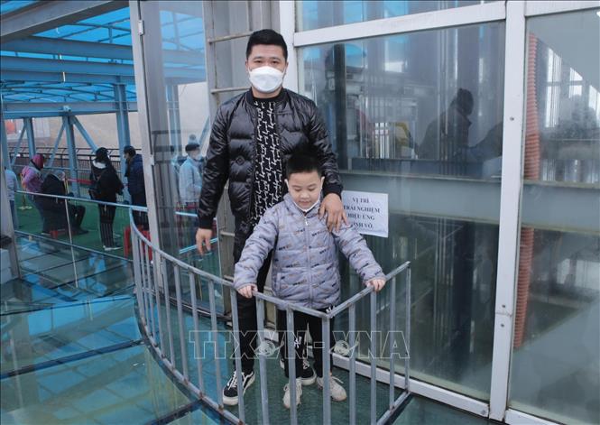 Trong ảnh: Một số du khách sau khi được nhân viên giới thiệu về miếng kính do chủ đầu tư tạo ra nứt, vỡ cũng muốn được trải nghiệm cảm giác mạnh đồng thời chụp ảnh làm kỷ niệm tại cây cầu kính cao nhất Việt Nam vào thời điểm hiện tại. Ảnh: Quý Trung - TTXVN
