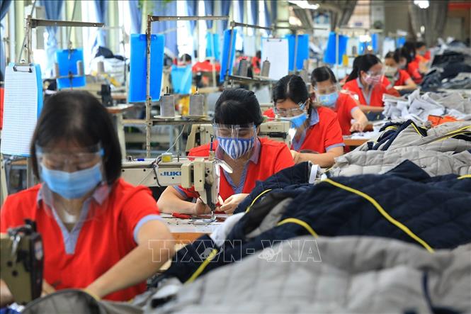 Trong ảnh: Công nhân Công ty CP may Chiến Thắng đảm bảo công tác phòng, chống dịch trong sản xuất. Ảnh: Tuấn Anh - TTXVN
