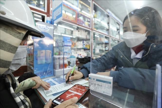 Chị Vân Anh (Đông Ngạc, Hà Nội) đi mua thuốc Molnupiravir điều trị cho 2 người thân bị mắc COVID-19. Ảnh: Minh Quyết - TTXVN