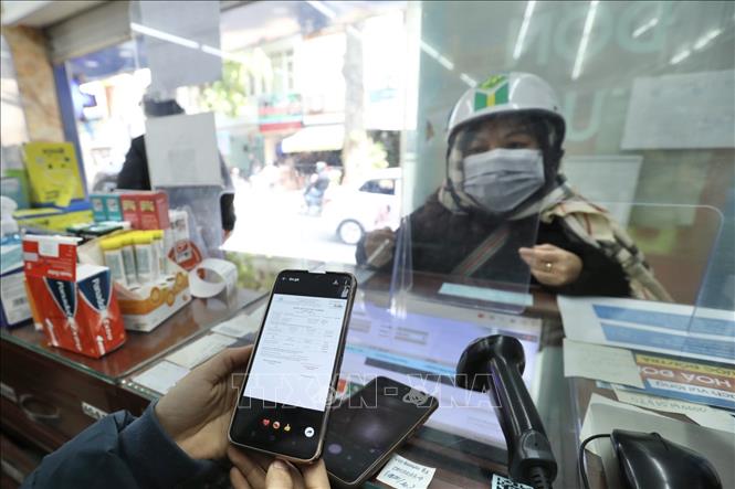 Nhân viên bán thuốc kiểm tra thông tin xác nhận F0 của khách đến mua thuốc thuốc Molnupiravir điều trị COVID-19 tại cửa hàng thuốc Long Châu (Hà Nội). Ảnh: Minh Quyết - TTXVN