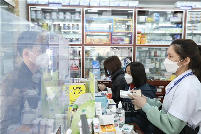 Nhân viên cửa hàng thuốc Long Châu giải thích cho khách về thuốc Molnupiravir điều trị COVID-19. Ảnh: Minh Quyết - TTXVN
