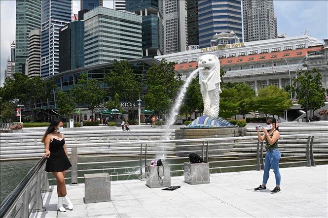 Trong ảnh: Khách du lịch chụp ảnh trước bức tượng Merlion ở Singapore. Ảnh: AFP/TTXVN