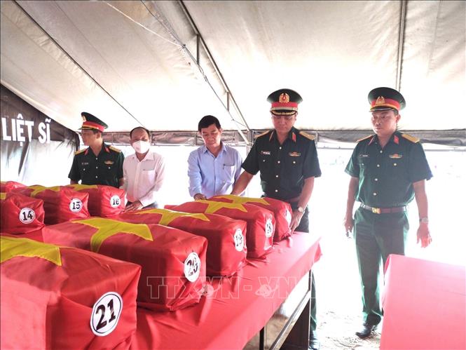 Lãnh đạo Quân khu 7, tỉnh Đồng Nai và  huyện Nhơn Trạch phủ quốc kỳ lên quách hài cốt liệt sĩ vừa tìm thấy. Ảnh: TTXVN phát