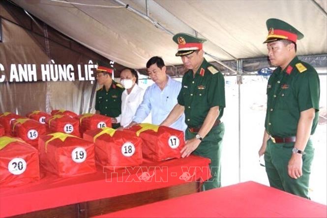 Lãnh đạo Quân khu 7, tỉnh Đồng Nai và  huyện Nhơn Trạch phủ quốc kỳ lên quách hài cốt liệt sĩ vừa tìm thấy. Ảnh: TTXVN phát