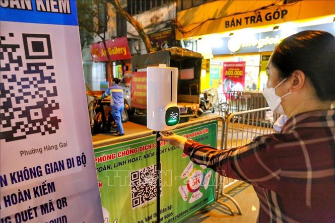 Người dân đo thân nhiệt trước khi vào phố đi bộ. Ảnh: Tuấn Đức - TTXVN