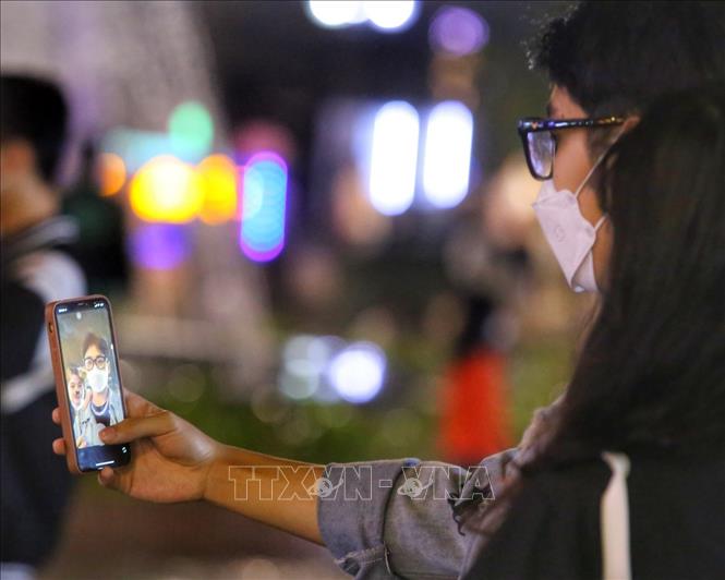 Các bạn trẻ chụp ảnh lưu niệm trên phố đi bộ hồ Hoàn Kiếm. Ảnh: Tuấn Đức - TTXVN