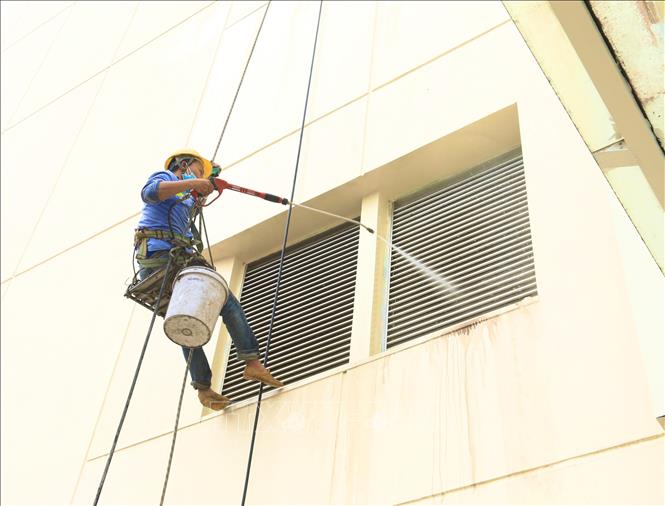 Trong ảnh: Công nhân đang vệ sinh bên ngoài Khu Thể thao dưới nước, nơi sẽ diễn ra các nội dung Bơi, Nhẩy cầu, Lặn tại Đại hội Thể thao Đông Nam Á 2021 (SEA Games 31). Ảnh: Hoàng Hiếu – TTXVN