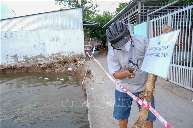 Người dân để biển cảnh báo nguy hiểm tại điểm sạt lở. Ảnh: Thanh Liêm - TTXVN