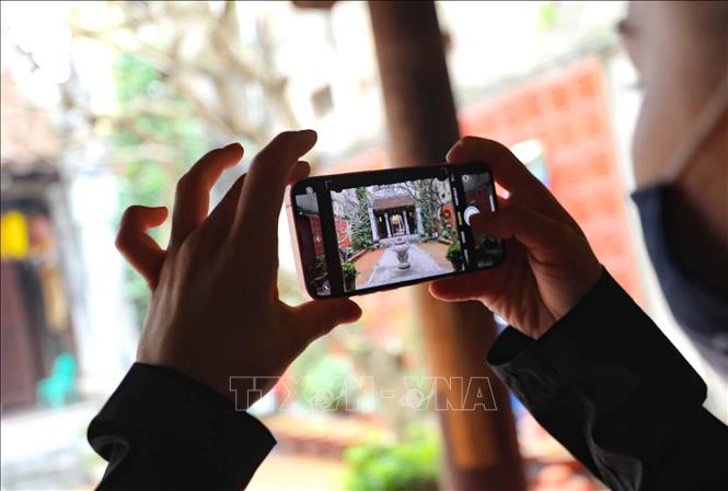 Du khách quốc tế lưu lại những hình ảnh đẹp khi ghé thăm đình Kim Ngân. Ảnh: Thanh Tùng - TTXVN
