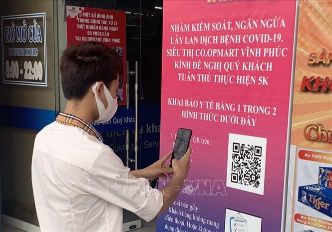 Trong ảnh: Khách hàng thực hiện quét mã QR khai báo y tế trước khi vào siêu thị Co.opmart Vĩnh Phúc. Ảnh: Hoàng Hùng - TTXVN