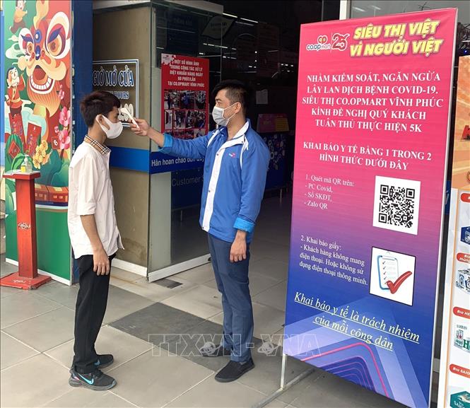 Trong ảnh: Đo thân nhiệt cho khách hàng trước khi vào siêu thị Co.opmart Vĩnh Phúc. Ảnh: Hoàng Hùng - TTXVN