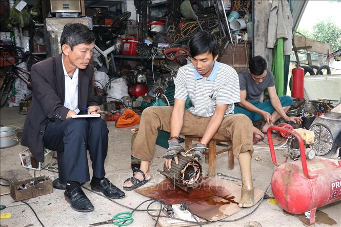 Nạn nhân bom mìn Trương Hồng Hoàn (sinh năm 1984), ở thôn Tây, xã Hiền Ninh, huyện Quảng Ninh, tỉnh Quảng Bình (giữa ảnh) vươn lên trong cuộc sống với nghề điện. Ảnh: Anh Tuấn – TTXVN