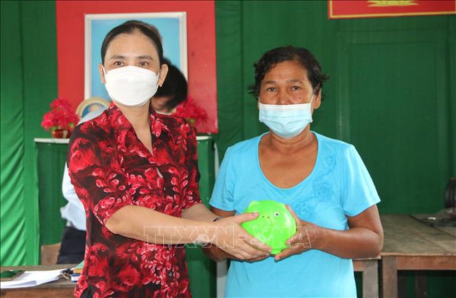 Bà Huỳnh Thị Lệ, Chi hội trưởng Chi hội phụ nữ ấp Đồng Khoen, xã Phong phú, huyện Cầu Kè (bên trái) trao heo đất cho bà Thạch Thị Sưa, ấp Đồng Khoen. Ảnh: Thanh Hòa - TTXVN