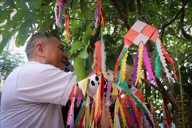 Photo: A visitor ties his wish written on a piece of colourful string after praying at the Then festival. VNA Photo: Nguyễn Oanh