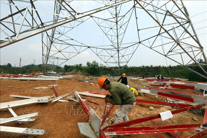 Các công nhân đang lắp dựng cột trên tuyến. Ảnh: Huy Hùng – TTXVN
