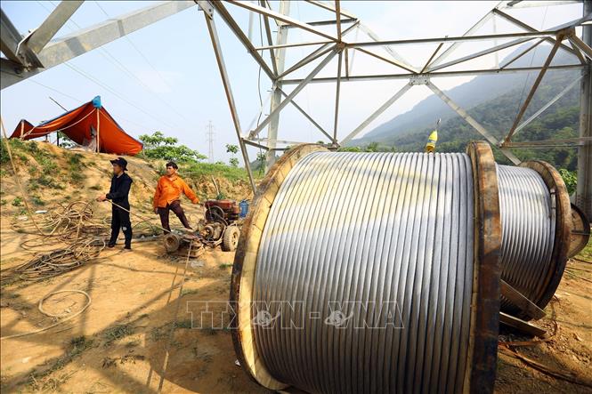 Công nhân đang tiến hành kéo dây tại vị trí cột 21, địa bàn huyện Bảo Thắng. Ảnh: Huy Hùng – TTXVN
