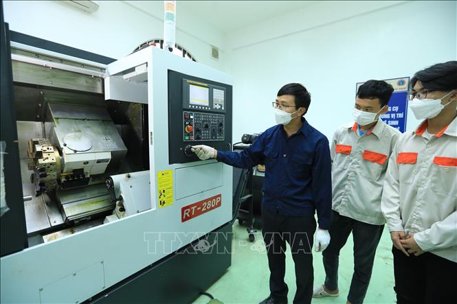 Trong ảnh: Giảng viên Khoa Công nghệ kỹ thuật cơ khí hướng dẫn sử dụng máy tiện CNC. Ảnh: Hoàng Hiếu - TTXVN