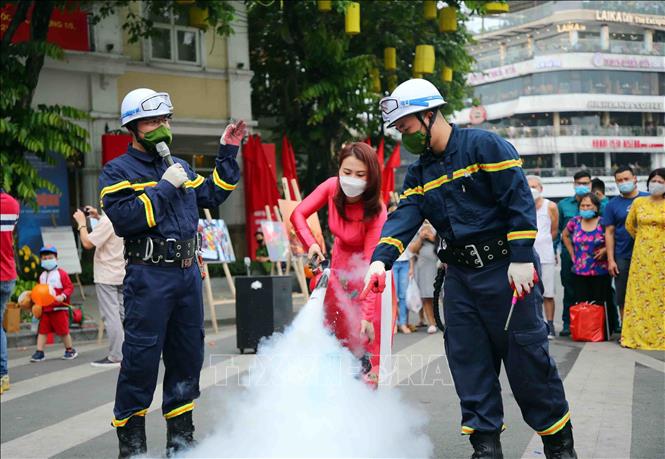 Trong ảnh: Cán bộ, chiến sĩ cảnh sát PCCC và CNCH quận Hoàn Kiếm hướng dẫn người dân sử dụng bình chữa cháy. Ảnh: Phạm Kiên - TTXVN