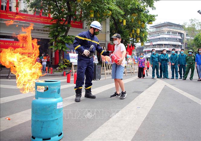 Trong ảnh: Cán bộ, chiến sĩ cảnh sát PCCC và CNCH quận Hoàn Kiếm hướng dẫn các em nhỏ sử dụng bình chữa cháy. Ảnh: Phạm Kiên - TTXVN