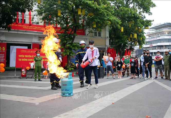 Trong ảnh: Cán bộ, chiến sĩ cảnh sát PCCC và CNCH quận Hoàn Kiếm hướng dẫn các em học sinh sử dụng bình chữa cháy. Ảnh: Phạm Kiên - TTXVN