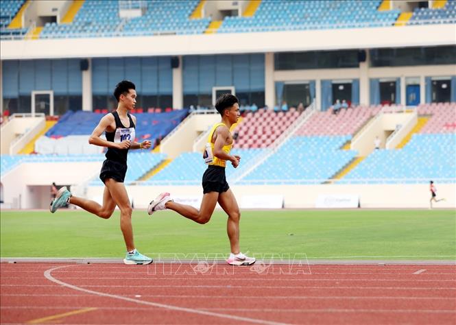 VĐV Đào Minh Trí (áo đen, đội Tuyển trẻ Nhổn) đoạt Huy chương Đồng và VĐV Tòng Văn Hoàn (áo vàng, đội Tuyển trẻ Nhổn) đoạt Huy chương Bạc nội dung chạy 5.000m nam. Ảnh: Phạm Hậu - TTXVN
