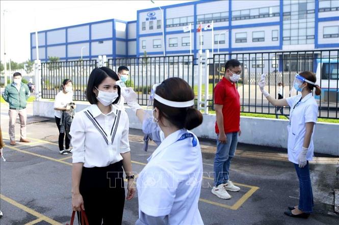 Công nhân và khách vào làm việc tại Công ty TNHH Optrontec Vina (KCN Bá Thiện 2, Vĩnh Phúc) được kiểm tra thân nhiệt để đảm bảo phòng, chống dịch. Ảnh: TTXVN
