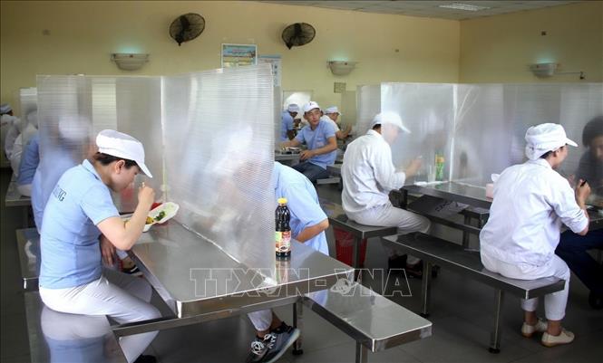 Tại nhà ăn trong KCN Hòa Khánh, thành phố Đà Nẵng, các công nhân được bố trí ngồi ăn giãn cách, có vách ngăn để đảm bảo phòng, chống dịch. Ảnh: TTXVN