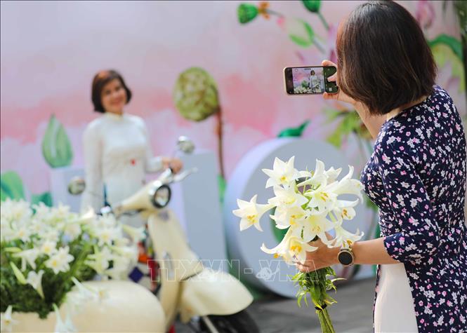 Ngày nghỉ lễ cũng là dịp để chị em phụ nữ xúng xính áo dài cùng lưu lại những khoảnh khắc đẹp của Hà Nội trong mùa hoa loa kèn. Ảnh: Thanh Tùng - TTXVN