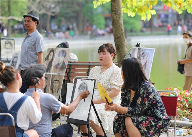 Du khách làm mẫu để có bức ký họa làm kỷ niệm cho mình khi đến với Hồ Gươm. Ảnh: Thanh Tùng - TTXVN