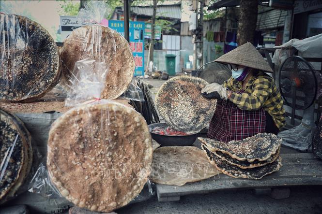 Công đoạn nướng bánh đa Kế đòi hỏi phải lật lên lật xuống kết hợp uốn nắn, chỉnh sao cho bánh tròn đều, chuyển sang màu vàng nhạt và dậy mùi thơm. Ảnh: Danh Lam-TTXVN