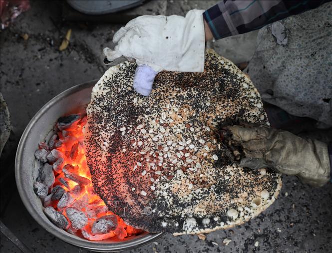 Công đoạn nướng bánh đa đòi hỏi phải lật lên lật xuống kết hợp uốn nắn, chỉnh sao cho bánh tròn đều chuyển sang màu vàng nhạt và dậy mùi thơm. Ảnh: Danh Lam-TTXVN