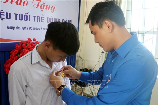 Phó Bí thư Tỉnh đoàn, Chủ tịch Hội Sinh viên, Chủ tịch Hội đồng đội tỉnh Nghệ An Thái Minh Sỹ gắn Huy hiệu cho em Đặng Ngọc Thái An. Ảnh: TTXVN phát