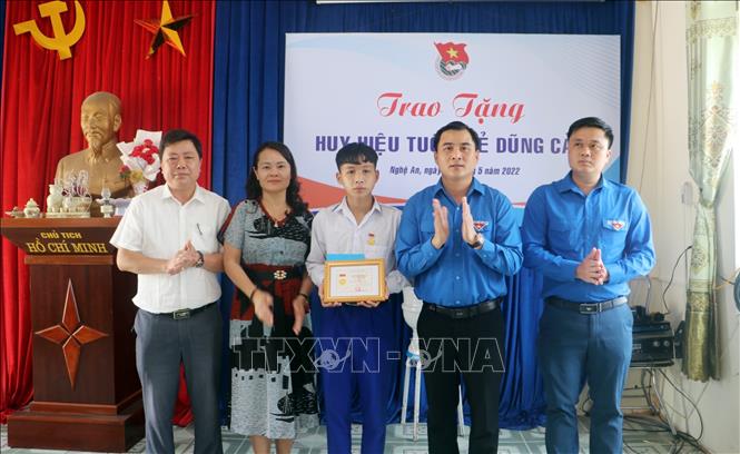 Phó Bí thư Tỉnh đoàn, Chủ tịch Hội Sinh viên, Chủ tịch Hội đồng đội tỉnh Nghệ An Thái Minh Sỹ (thứ 2 từ phải sang) trao tặng Huy hiệu cho em Đặng Ngọc Thái An. Ảnh: TTXVN phát