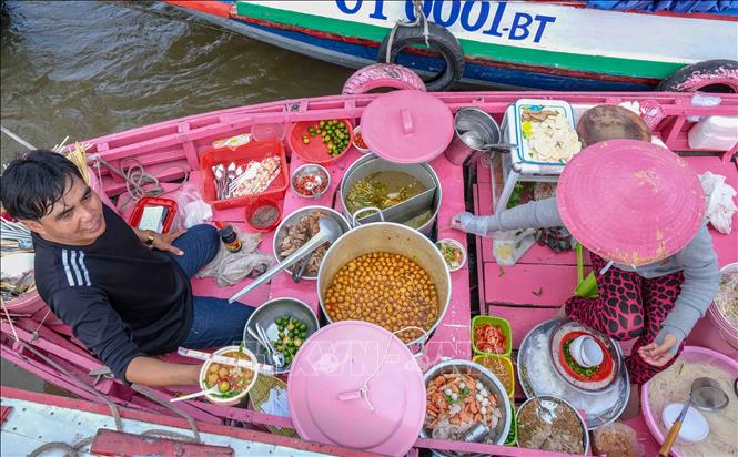 Trong ảnh: Vợ chồng chủ nhân chiếc ghe hồng luôn tay phục du du khách đến tham quan chợ nổi Cái Răng vào mỗi sáng sớm. Ảnh: Thanh Liêm - TTXVN