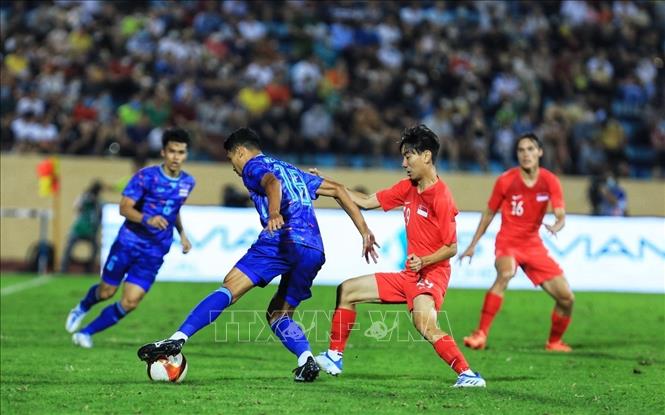 Weerathep Pomphun (18) của U23 Thái Lan nỗ lực đi bóng trước sự truy cản của cầu thủ U23 Singapore. Ảnh: Tuấn Anh - TTXVN