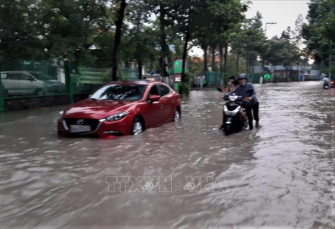 Một người dân cố vượt qua đoạn ngập khiến xe bị chết máy phải dẫn bộ. Ảnh: Chí Tưởng - TTXVN
