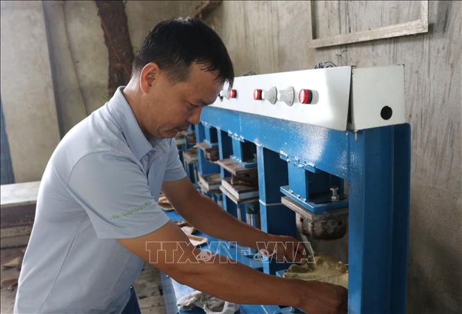 Mr. Tuyen makes the dishes from pressing sea grape leaves together using a pressing machine. VNA Photo: Phạm Cường