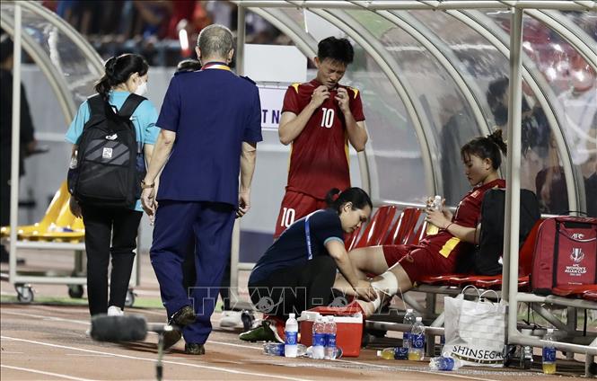 Chăm sóc y tế cho Lương Thị Thu Thương (số 2) bị đau, phải rời sân sau một pha va chạm với cầu thủ đối phương. Ảnh: Hoàng Linh - TTXVN